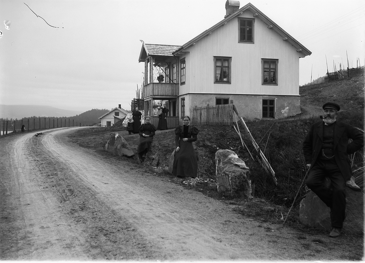 Kristoffer Horne, ØRBEKK, LANGS HOVEDVEGEN GJENNOM RING/BRØTTUM i Ringsaker, FRA VENSTRE: JULIE ØRBÆK, ANNE ØRBÆK, ELISE SJØLI OG ERIK FRENG. HUSET I BAKGRUNNEN ER SJØLI HVOR DET VAR SMIE. Sveitserstilhus, halvannen etasje med kjeller på bakken, to etasjes veranda med takflis og dragestil.