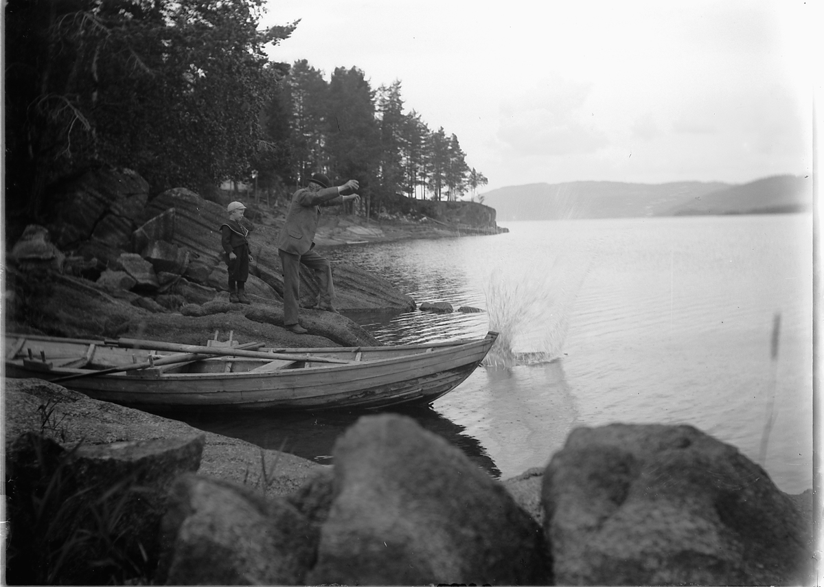 Kristoffer Horne, ROBÅT, FRITID, MJØSA. Mann og gutt kaster stein i vannet.