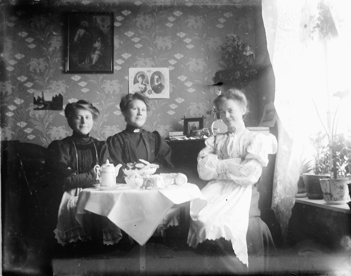 Johs. (Johannes) Johannessen, Interiør, stue. Tre kvinner sitter i en sofa og drikker kaffe. Fra venstre: Louise Johannessen (siden gift Finsdal er datter av bakermester Olaus og Lovise Johannessen) (1887-1954), Paula , Aagoth Morbech Johannessen.