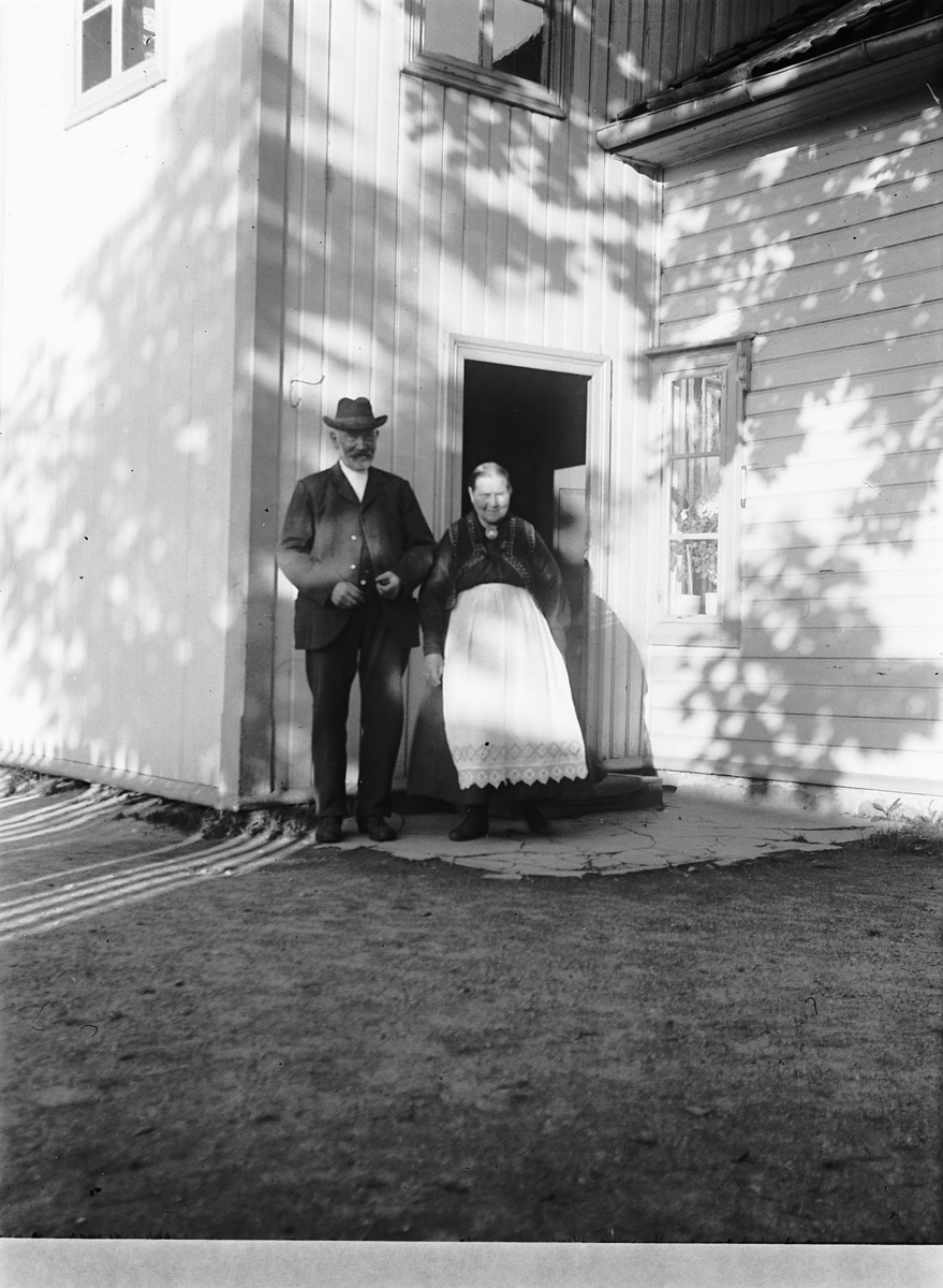 Ragnvald Andersen, Eldre ektepar foran inngangsdøra. Lokfører Mathias Andersen og hustru Syverine. Fotografens foreldre. Antatt sted, Granberg, Vang i Hamar.