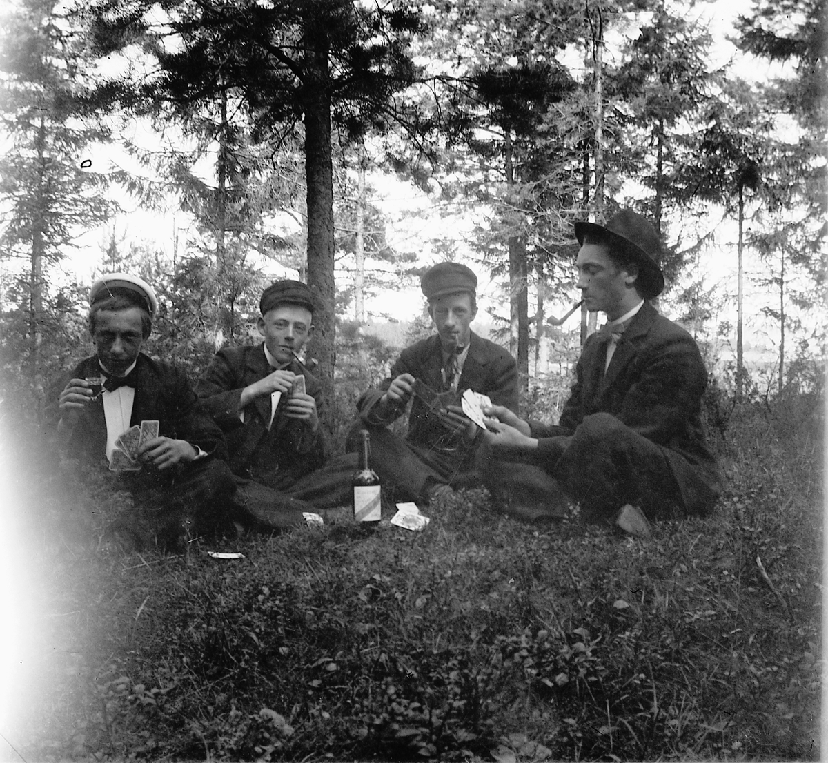 Ragnvald Andersen, Eksteriør, skog. Fire unge menn drikker, røyker og spiller kort.