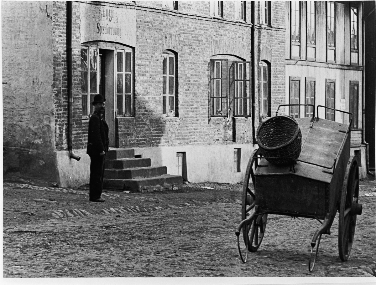 Hans Emil Erichsen, Grønnegata 61-63 i Hamar. Folk. Håndkjerre. Røverborgen til venstre.