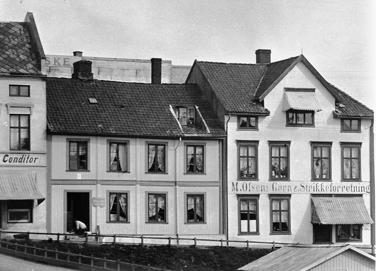 Hans Emil Erichsen, Østre torg. Bebyggelsen langs Grønnegata i Hamar. M.Olsens Garn & Strikkeforretning. Utsnitt.