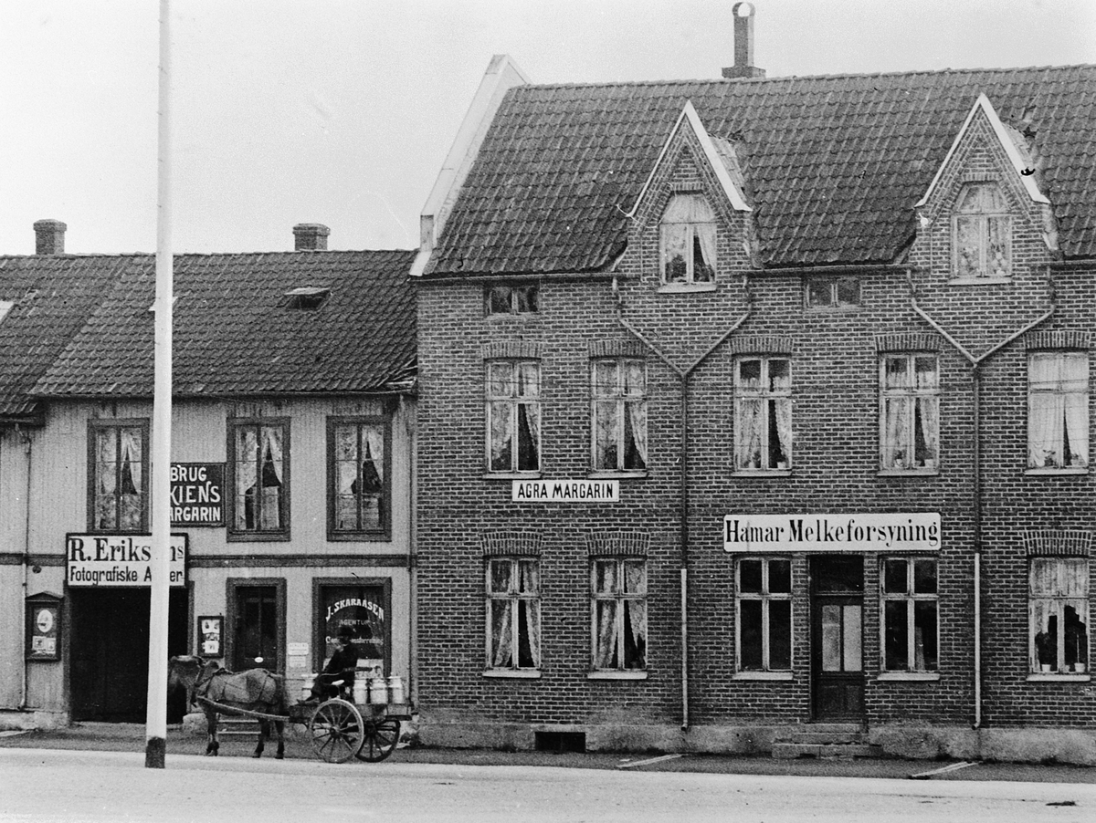 Hans Emil Erichsen, Østre Torg i Hamar med bebyggelsen langs Vangsvegen. Hamar Melkeforsyning, Agra Margarin reklame, R. Eriksens Fotografiske Atelier. J. Skaraasen Agentur. Hest og kjerre med melkespann. Utsnitt.