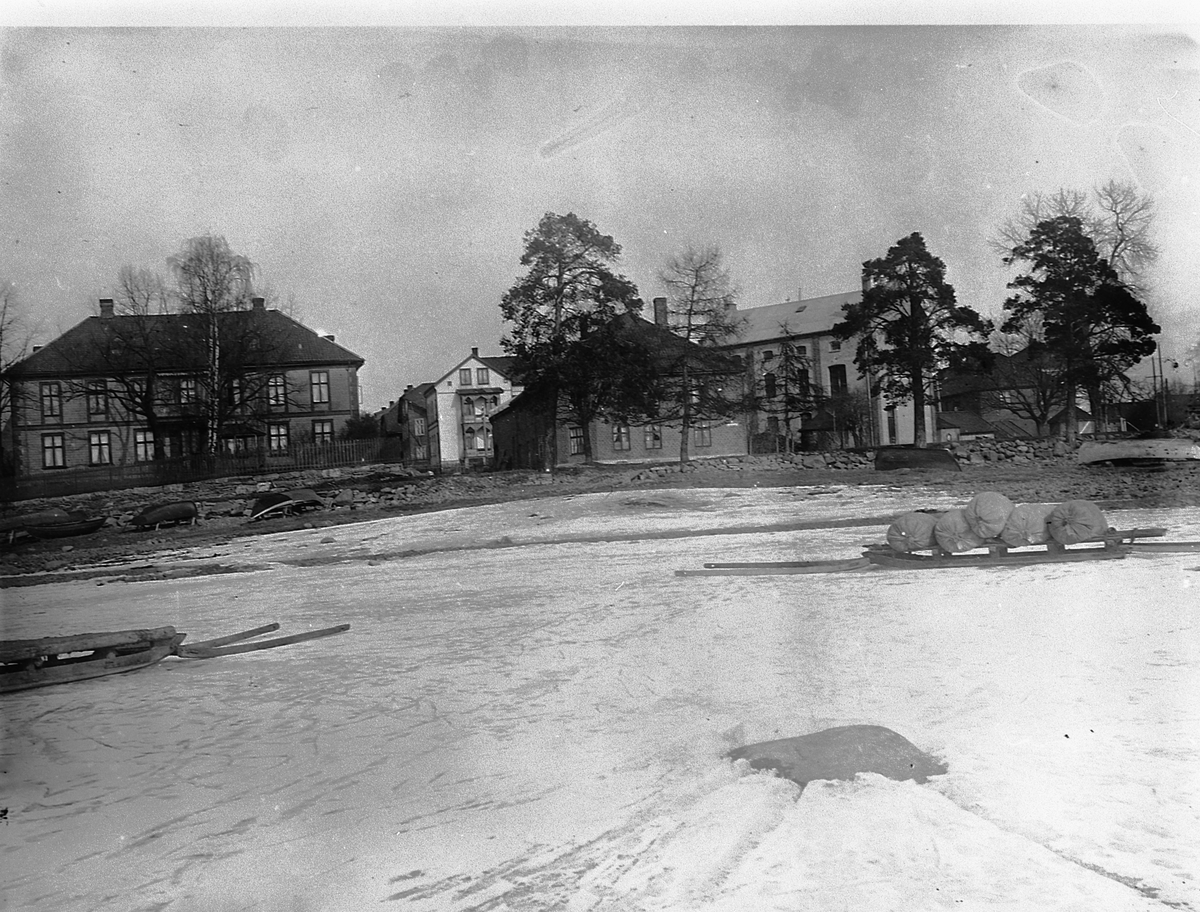 Hans Emil Erichsen, Ekely. Høiensalodden med Heidemannsgate 1,2,3 i Hamar. Vinterbilde. Sleder på isen i forgrunnen.