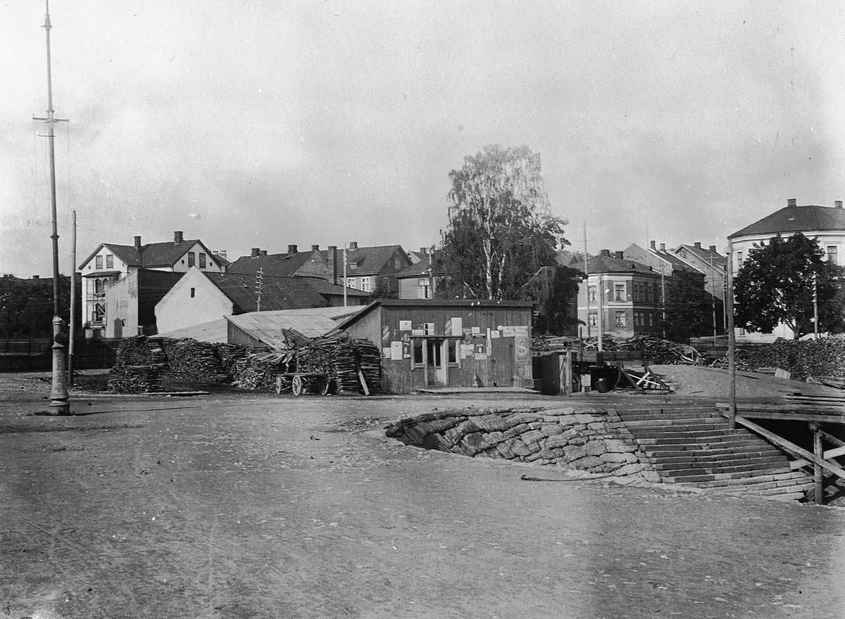 Hans Emil Erichsen, Hamar Brygge på Høiensalodden. Ekspedisjonslokale og vedlager. Bebyggelsen i Vestbyen i bakgrunn.