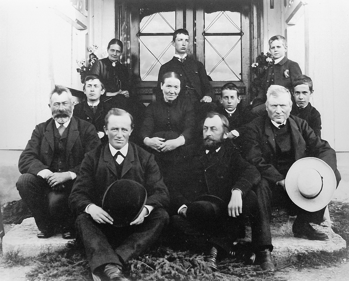 Hans Emil Erichsen, Gruppebilde fra verandaen på Buttekvern i 1890 åra. Foran fra venstre er Jens Buttekvern, J.M. Narud, prost Hans Emil Erichsen. Den fjerde mannen er ukjent. I midten sitter Karen Torsæter som var husholdererske på Buttekvern i mange år. Damen til venstre bak er fru Erichsen. de 5 guttene er ektepar…