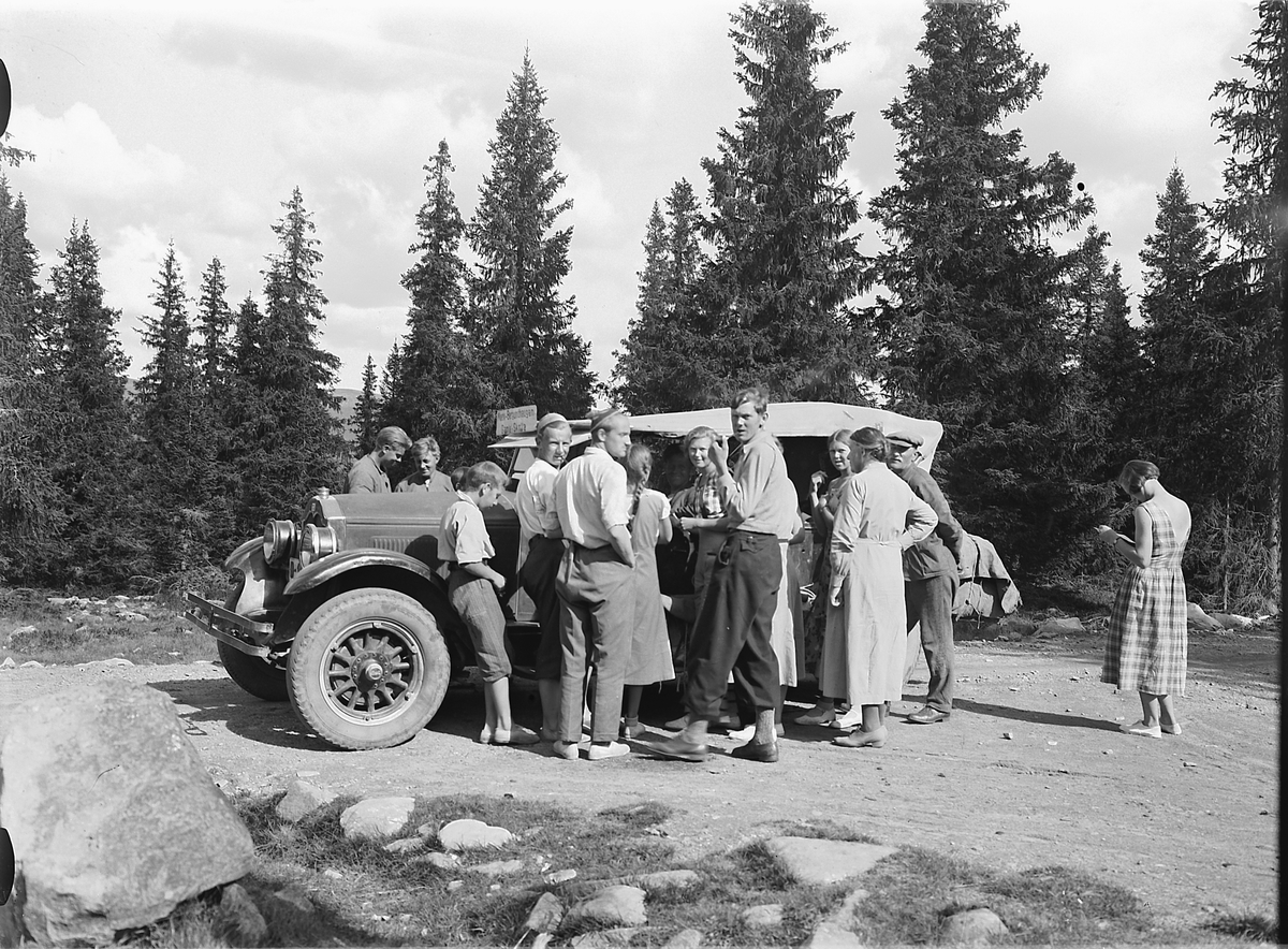 Simen Baardseth, Eksteriør, vei i skogen. Gruppe mennesker samlet rundt en rutebil med skilt Moelv-Bergundhaugen-Gamle Skolla. Buick 1927-28. Den tilhørte i 1930 Gunnar Grøtlien, Moelv iflg. Bilboken for Norge 1930.