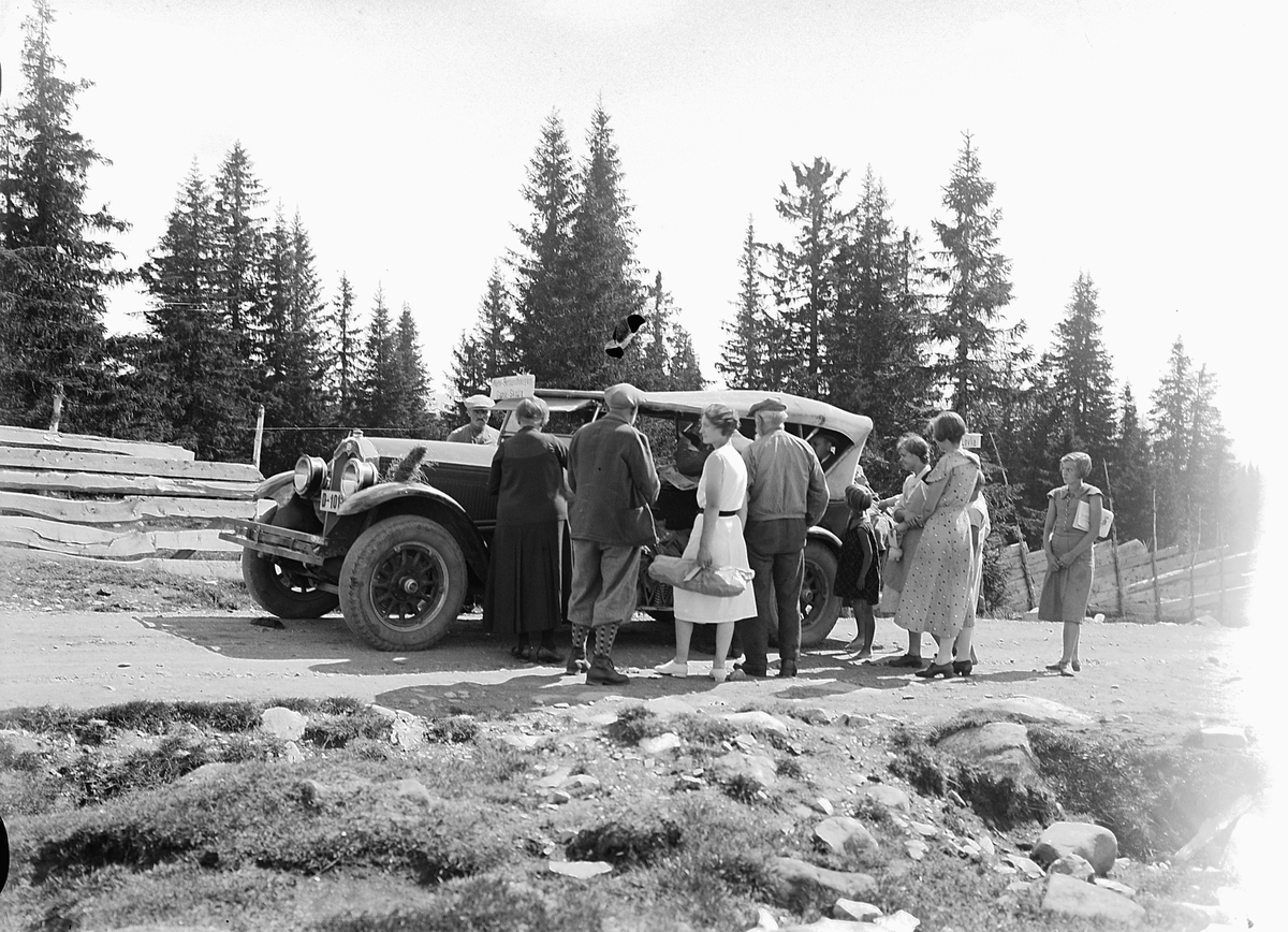 Simen Baardseth, Eksteriør, vei i skogen. Gruppe mennesker samlet rundt en rutebil med skilt Moelv-Bergundhaugen-Gamle Skolla.