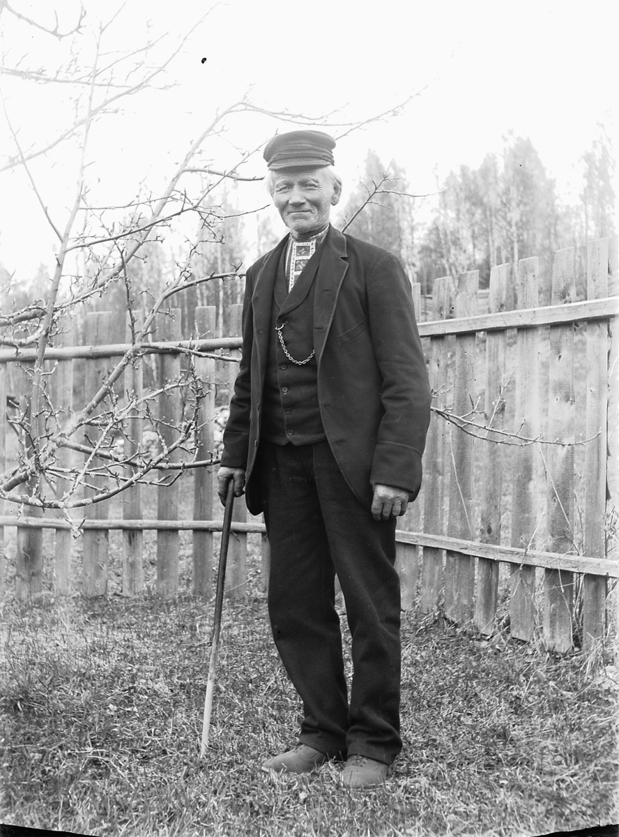 Simen Baardseth, Eldre mann med stokk i en hage med gjerde.