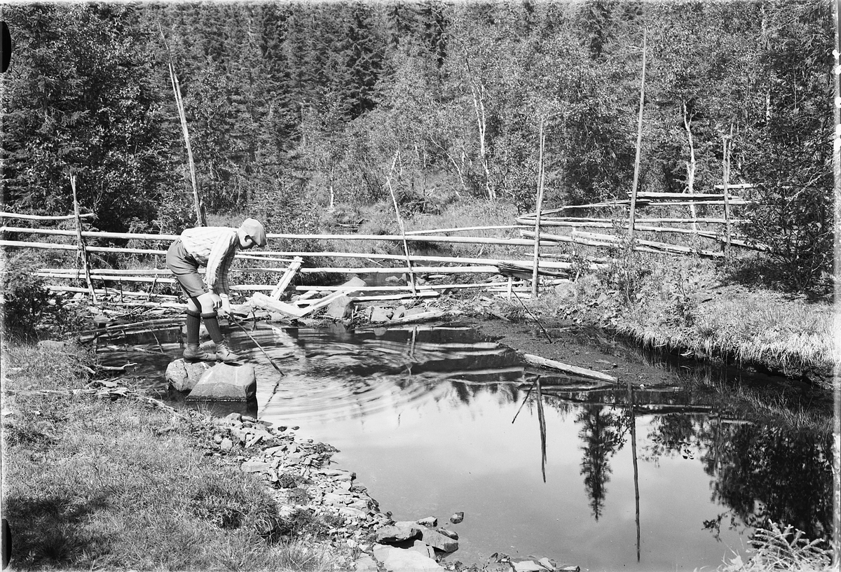 Simen Baardseth, Gutt med en pinne ved en bekk, en skigard i bakgrunnen.