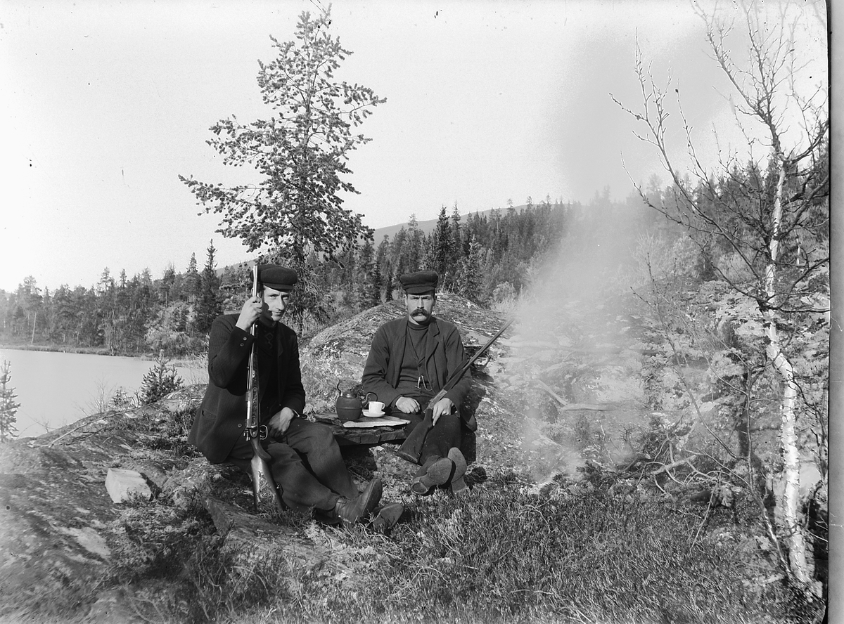 Simen Baardseth, Eksteriør, skog. Simen Baardseth og ukjent på jakt, drikker kaffe ved et bål. Våpen, kaffekanne.