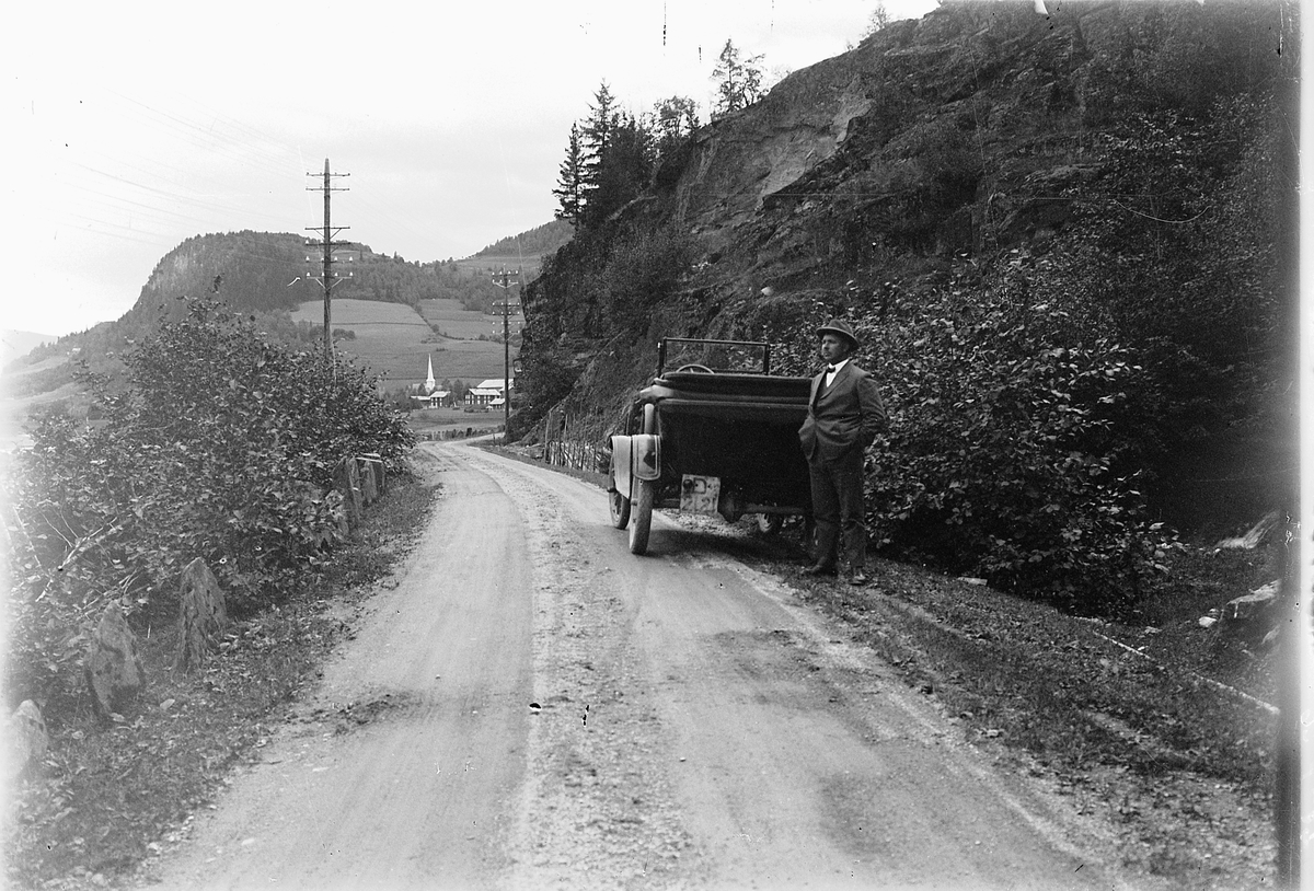 Simen Baardseth, H. J. Røed, lensmannsfullmektig, på biltur i Gudbrandsdalen. Fåvang kirke i Ringebu i bakgrunnen. Bil med reg. nr D-2121