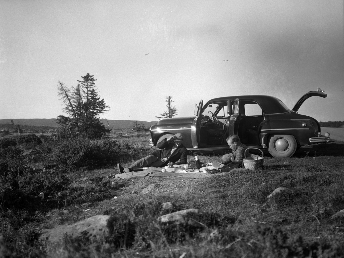 Kristian Heramb, To menn tar ei kaffepause under en biltur på fjellet. Bilen er en Dodge eller Plymouth, ny modell i 1949 som gikk relativt uendret til 1952.