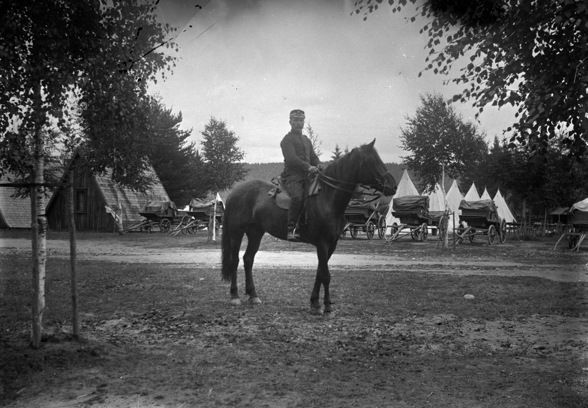 Johannes Larsen Alhaug, En soldat på hesteryggen. Telt og kjerrer i bakgrunnen.