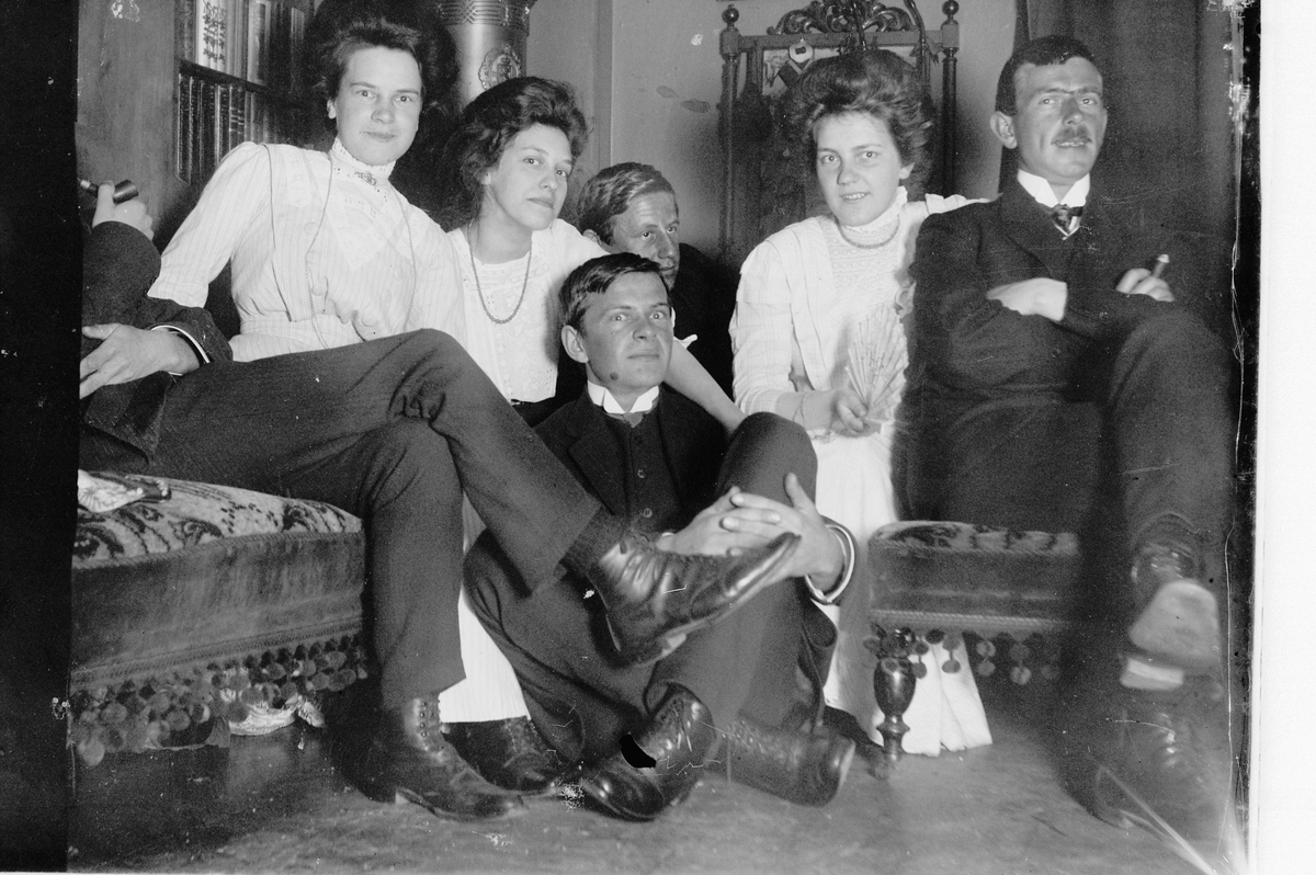 Hans Emil Erichsen, Gruppe kvinner og menn i stue. Ukjente.