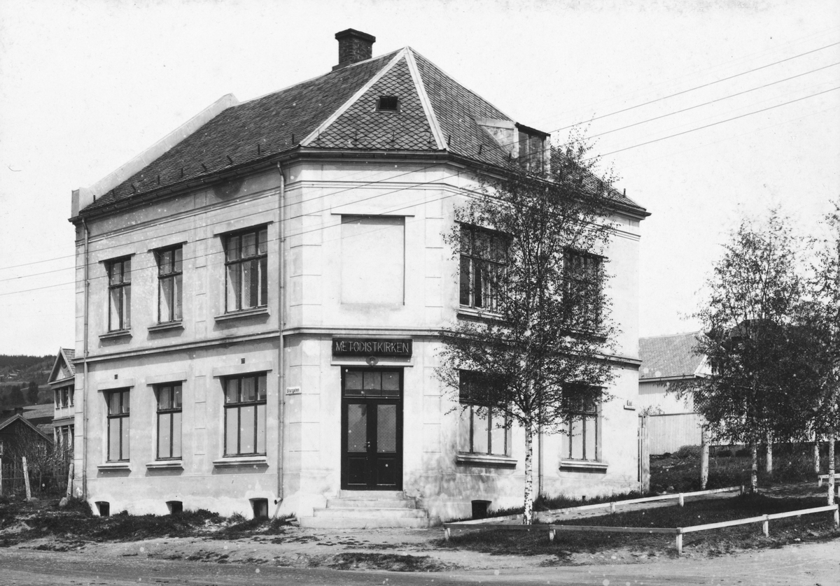 Ukjent, Metodistkirken i Lillehammer, 1923. Kirkehuset lå på et hjørne i Storgaten, lesbart navn på gateskilt Tekst skrevet bak på bildet. "Kirkebygningen i Lillehammer ved indvielsen 3. juni 1923. Eilert Bernhardt Pastor"