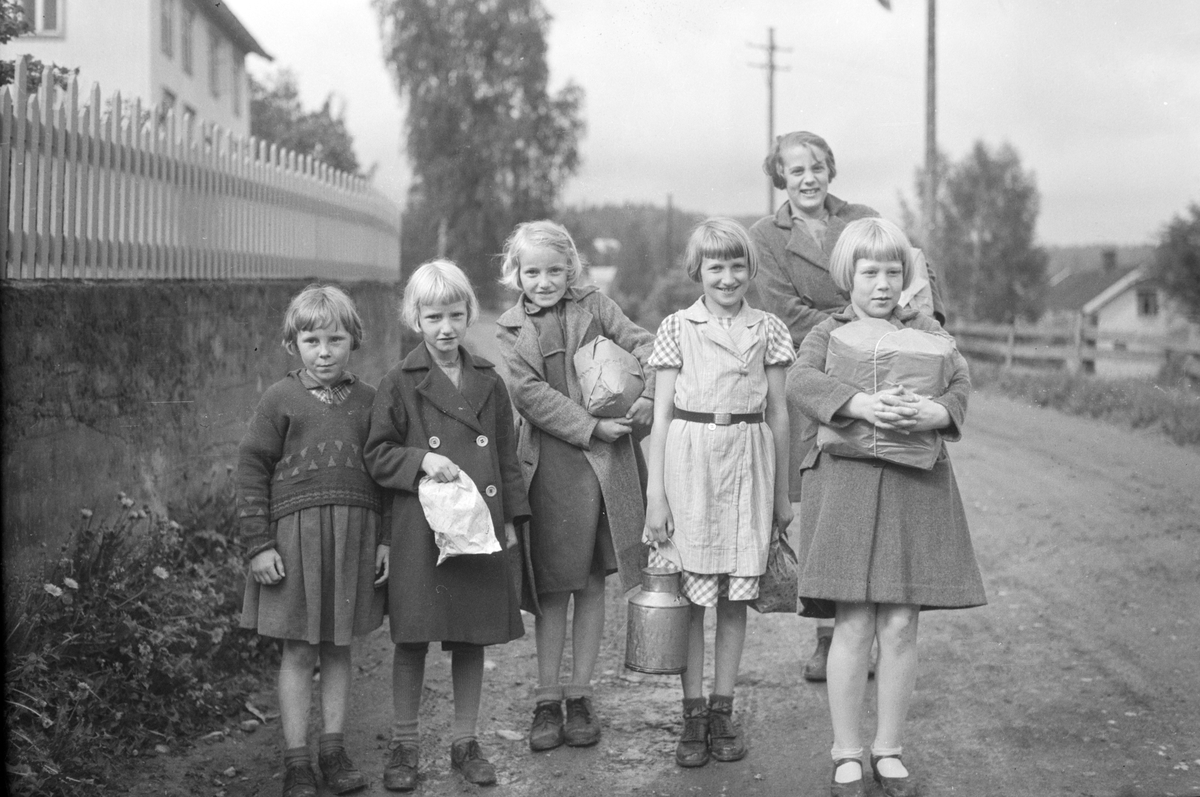 Håkon Prestkværn, Jenter på handletur 1938-1939. Foto tatt i Åsmarkvegen i Moelv, utenfor stakitten til Dalseth. Jentene som bodde litt lenger oppi i vegen hadde vært på handletur "neri Dala". Fra v. Magnhild Skogheim, Bergljot Granberg Roseth, Gerd Granberg Haugen, Reidun Nystuen Sandvold,, Astrid Hagen (bak) og Ge…