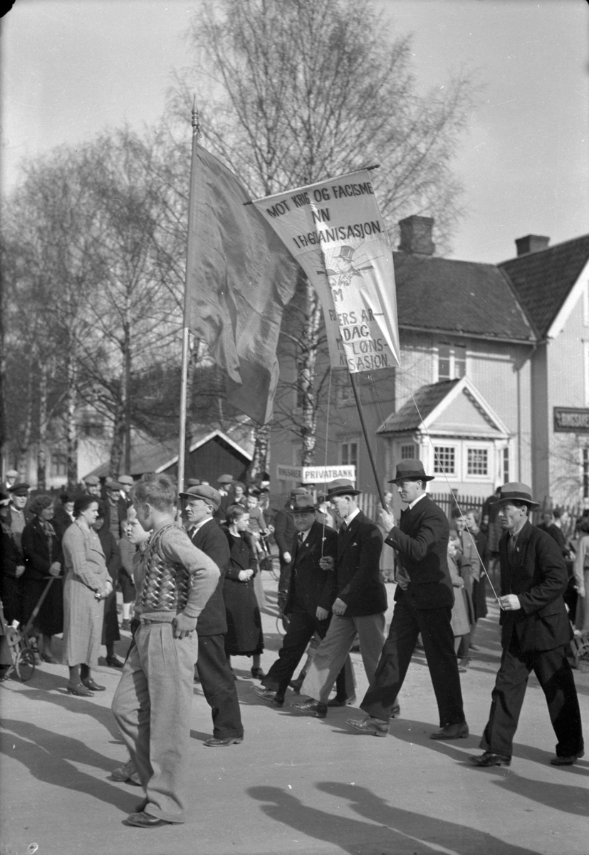 Håkon Prestkværn, 1. mai -toget i Moelv 1935-36 på hjørnet av Privatbanken. Fane med parole "Mot Krig og facisme" Reidar Dalseth under rødt flagg. Fag og arbeiderbevegelsen.