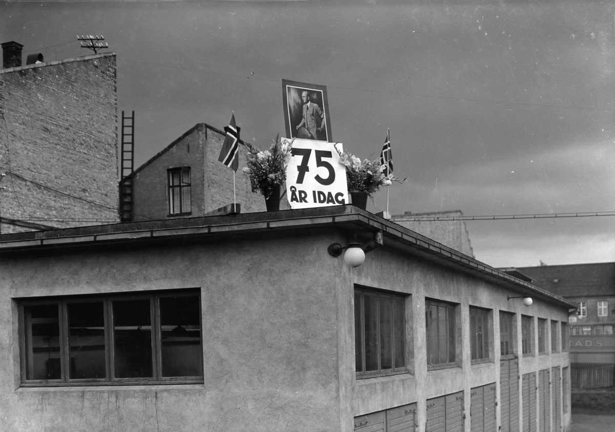 Normann Fotoatelier, Oplandske Auto. 75 års i dag. Jubileumsmarkering på taket. Hamar