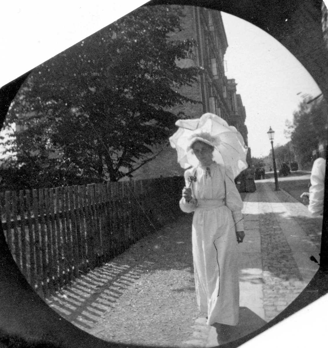Fredrik Carl Mülertz Størmer, Frk. Signe Faye Hansen spaserer på fortau langs gjerde, Oslo.