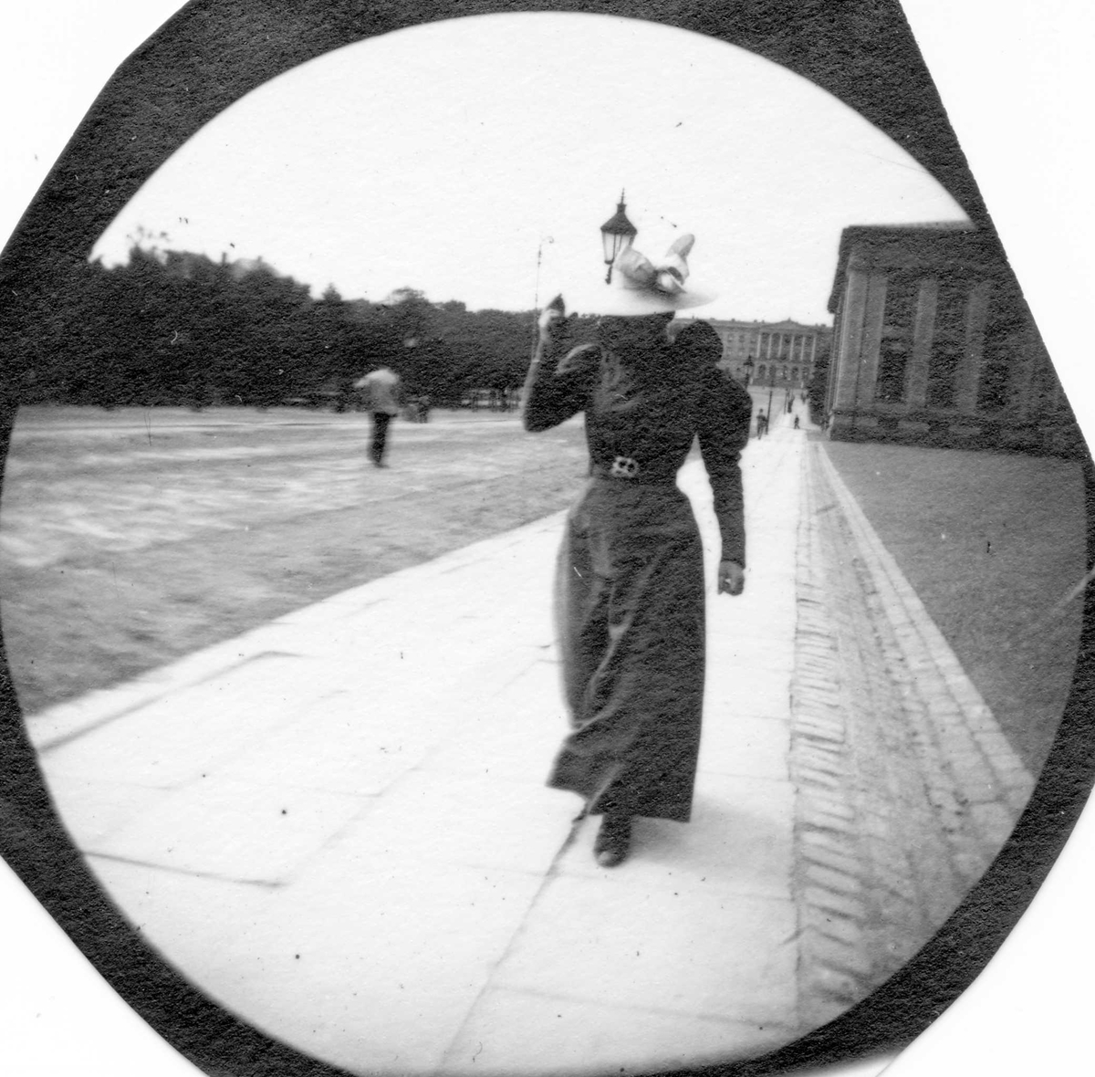 Fredrik Carl Mülertz Størmer, Frk. Heidenreich spaserer på fortau utenfor Universitet, Oslo, med Slottet i bakgrunn..