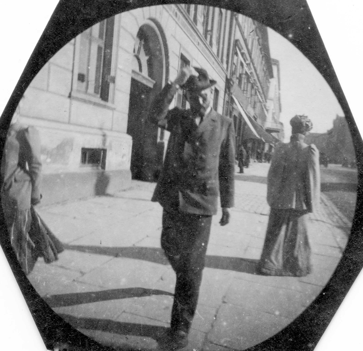 Fredrik Carl Mülertz Størmer, Adjunkt A. Andersen spaserer langs bygate, ant. Karl Johans gate, Oslo, med handa på hatten..