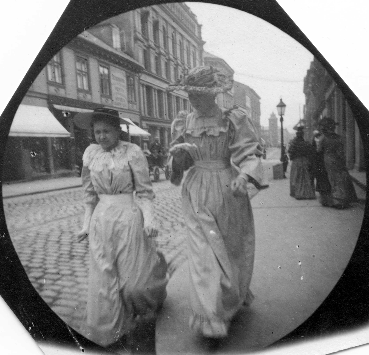Fredrik Carl Mülertz Størmer, To lyskledte damer spaserer i Karl Johans gate i Oslo. I bakgrunnen ser man branntårnet ved hovedbrannstasjonen.