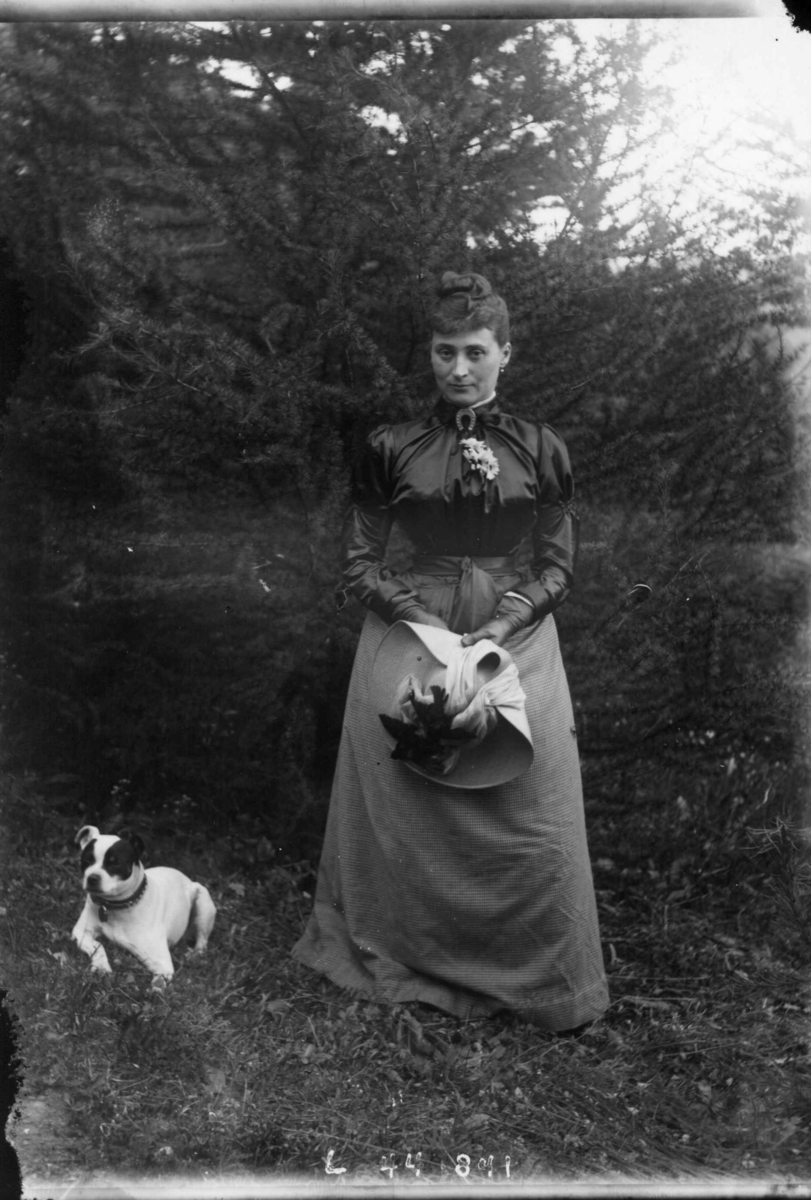 Fredrik Emil Faye, Portrett, fru Lovise Maurer, født Løvenskiold, ca. 1888, i hagen med hatt og hund. Fra portrettserie av personer som bodde på eller besøkte Dal gård, Ullensaker, fotografert av gårdens eier, kammerherre Fredrik Emil Faye (1844-1903) i årene 1875-1900.