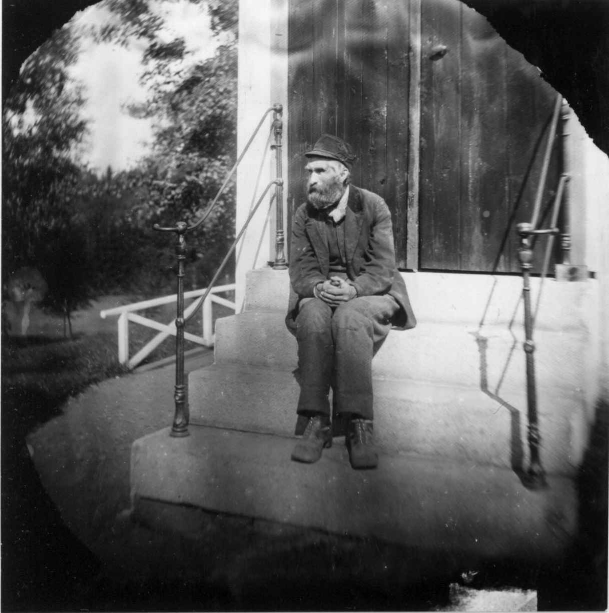 Fredrik Emil Faye, Arbeidsfolk, Dal gård, Ullensaker. Mann sittende på trapp. Fra portrettserie av personer som bodde på eller besøkte Dal gård, Ullensaker, fotografert av gårdens eier, kammerherre Fredrik Emil Faye (1844-1903) i årene 1875-1900.