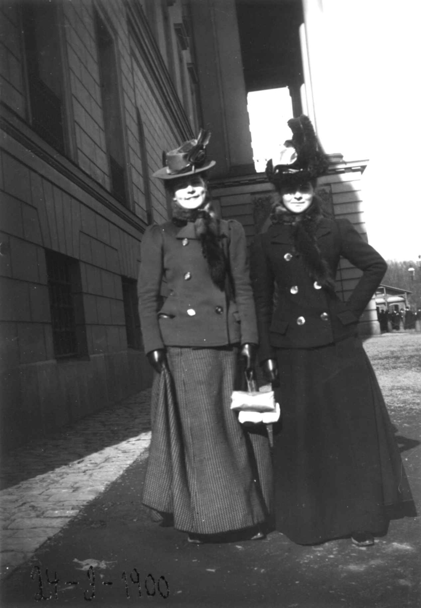 Fredrik Emil Faye, Dobbeltportrett, to kvinner foran Slottet, Oslo, 1900. Ragnhild Bogesen (ant., til venstre) og Anne Faye poserer i kåpe og hatt. Fra serie fotografert av kammerherre Fredrik Emil Faye (1844-1903), Dal gård, Ullensaker 1875-1900.