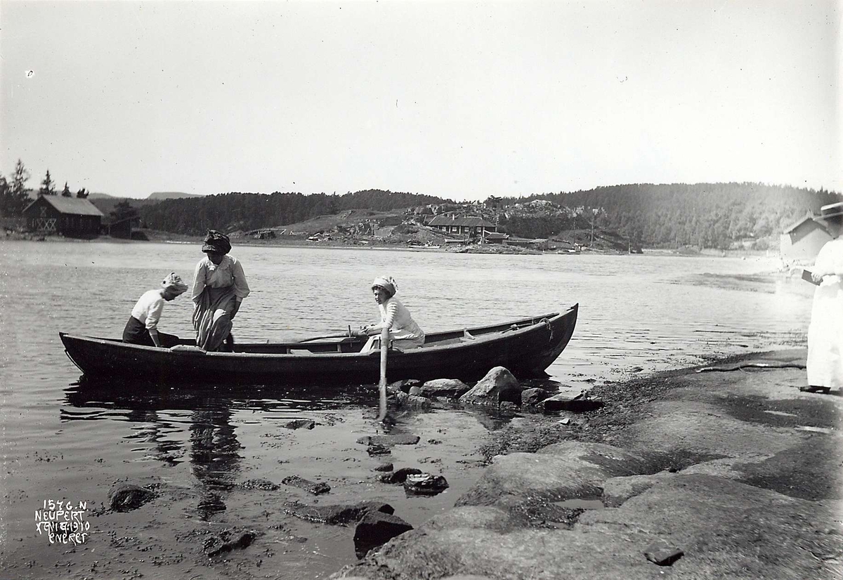 Hermann Christian Neupert, Ved Bygdøy Sjøbad, Oslo 1908. Oversiktsbilde.Tre kvinner på fjorden i pram, en kvinne står på stranda.