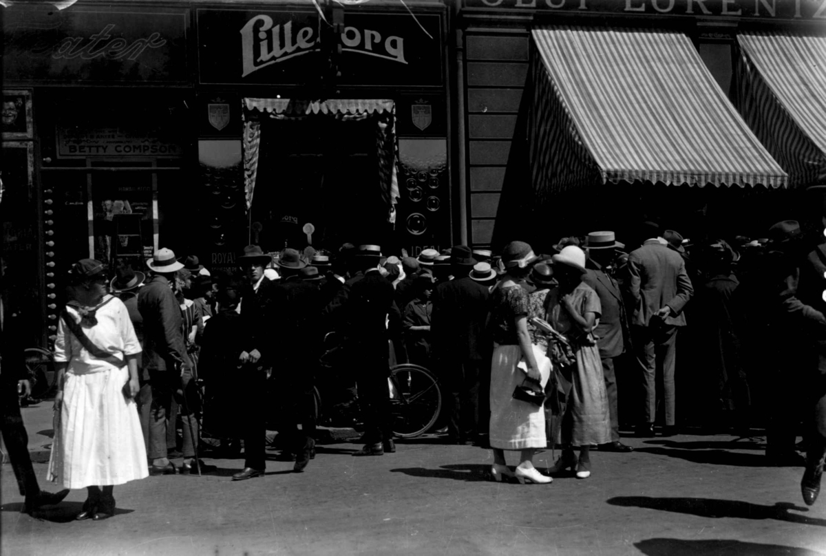 Hermann Christian Neupert, Sommerklær. Karl Johans gate, Oslo. 1924. Spaserende. menn og kvinner. Mann med sykkel.