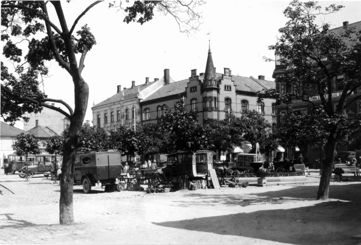 Hermann Christian Neupert, Sarpsborg. 1930. Torg. Torghandel? Biler. Bybebyggelse i bakgrunnen.