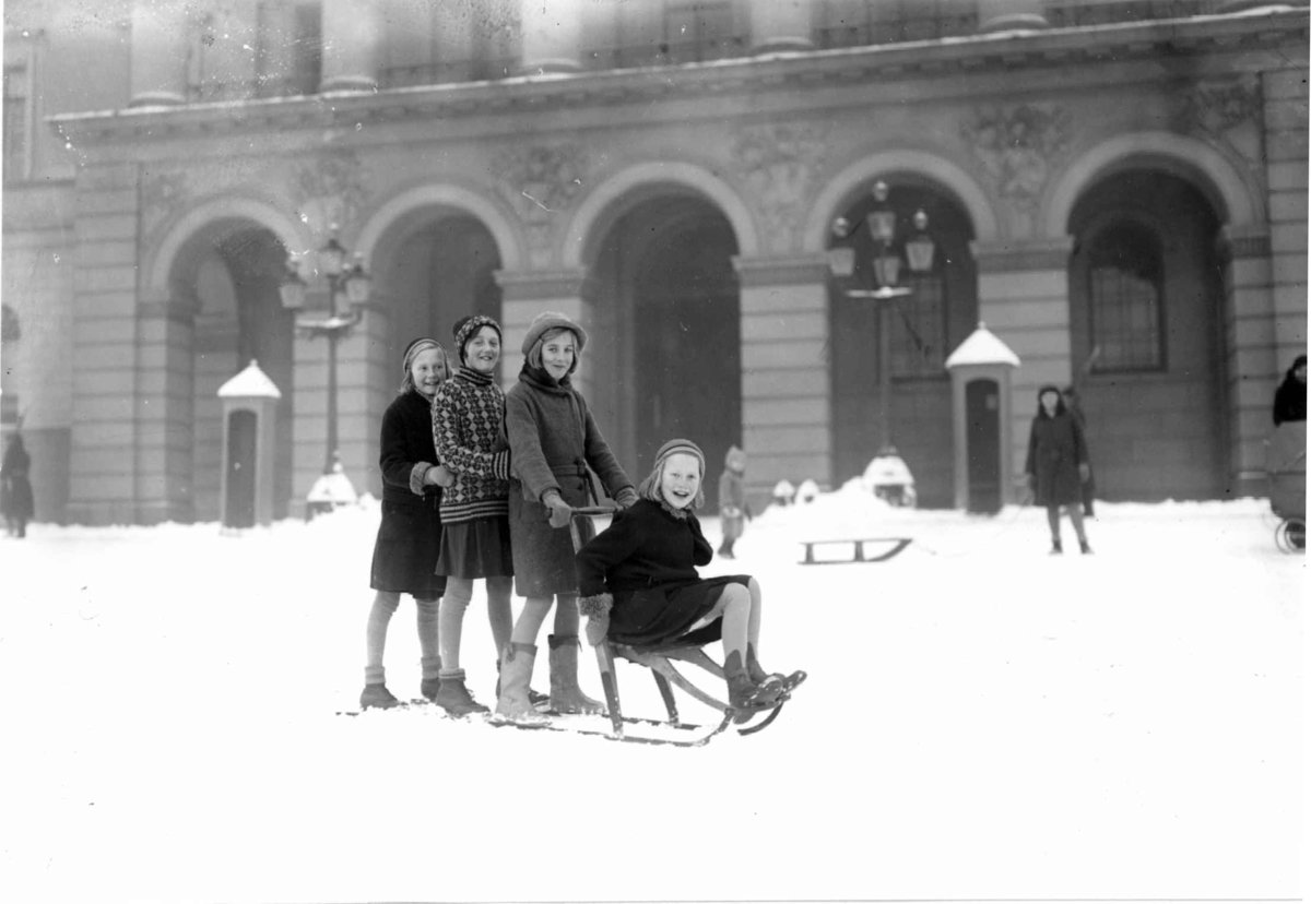 Hermann Christian Neupert, Oslo. På spark. Vintermotiv. 1930-1931. Piker på spark foran Slottet. Vakter i bakgrunnen.