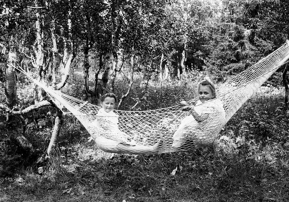 Robert Collett, Piker i hengekøye, begge i sommerkjoler, ukjent sted. Serie tatt av Robert Collett (1842-1913), amatørfotograf og professor i zoologi.