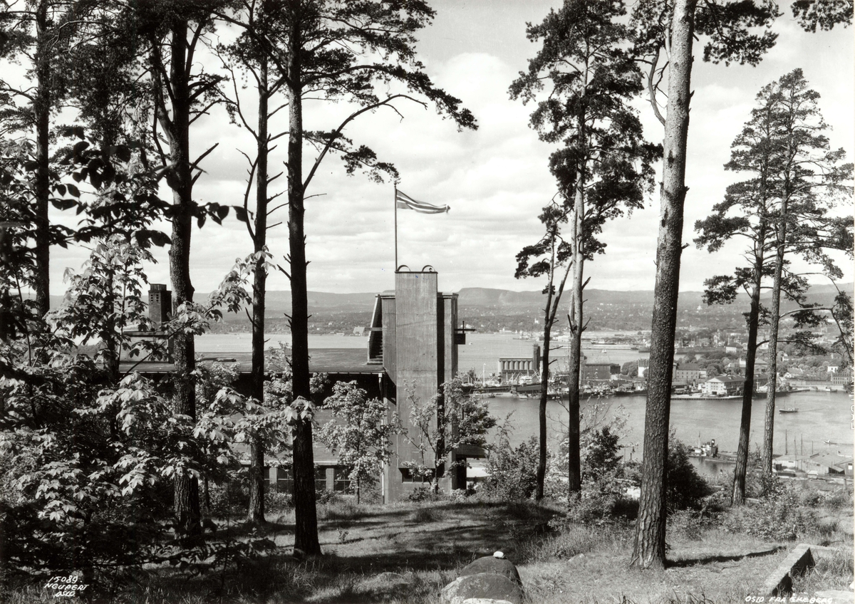 Hermann Christian Neupert, Ekeberg, Oslo 1937. Utsikt gjennom trærne til restauranten og mot Oslo havn og byen. Vimpel på restauranten.