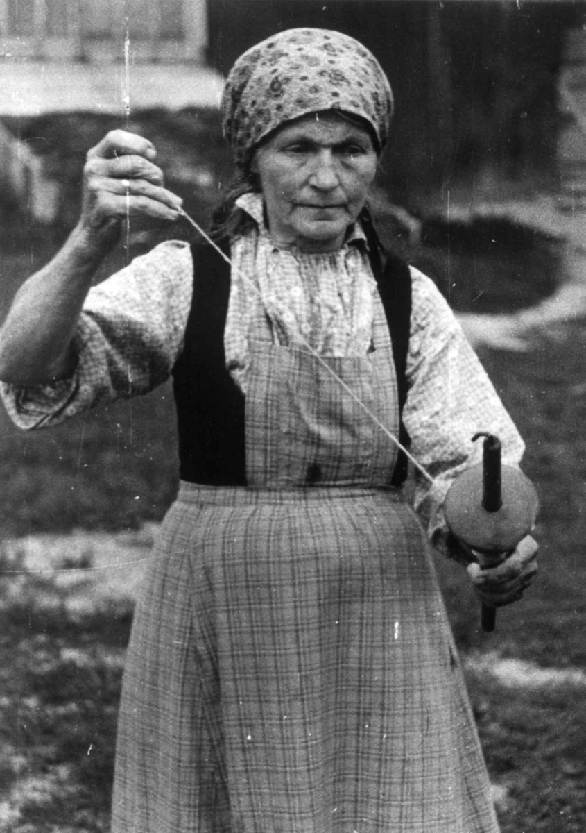 Anna Grostøl, Bø, Telemark 1940. Anne Østbø holder på med håndteinspinning.