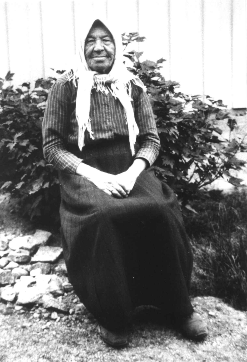 Anna Grostøl, Kvinne, ukjent, sitter foran en busk.Ukjent sted 1935.