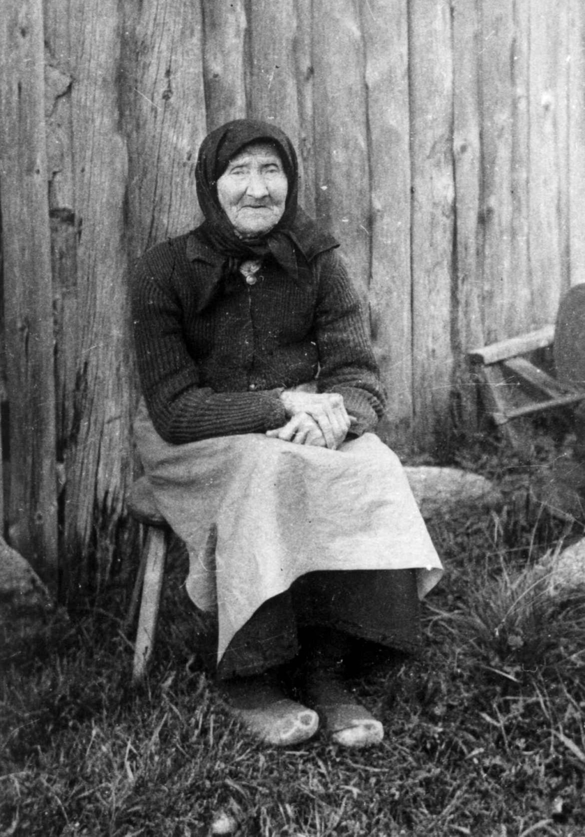 Anna Grostøl, Fru Anna Ånensdatter Grostøl sitter på en stol foran en husvegg. Eiken 1937.