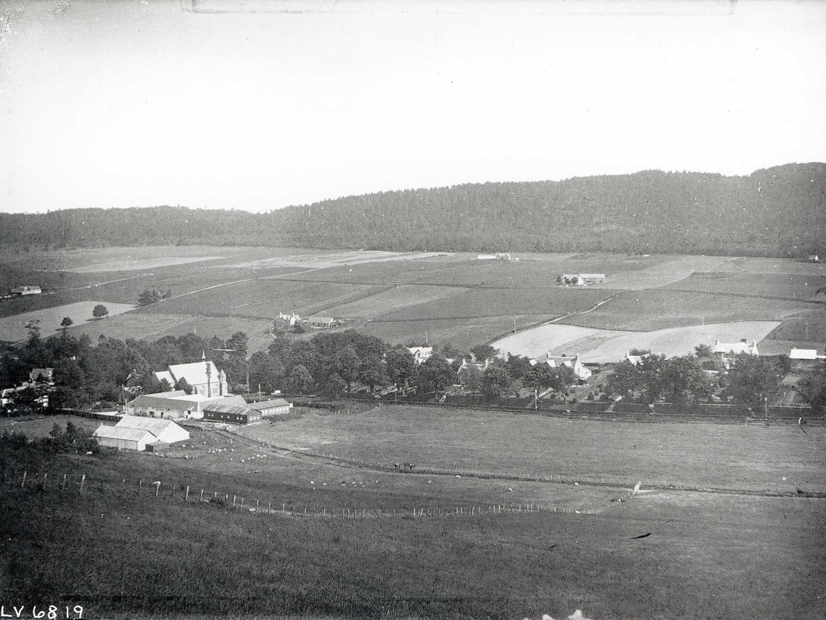 Tom Kent, Kirke, gårder med jorder og sauer, skog i bakgrunnen. Fodderty & Strathpeffer Parish Church, Highlands, Skottland.
