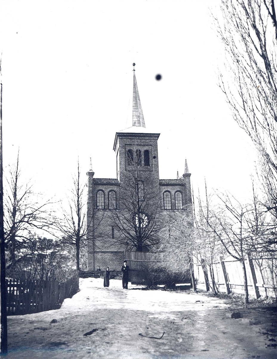 Tom Kent, Vei med gjerder går mot kirke. Spist tak på tårnet, små tårn på "skuldrene".