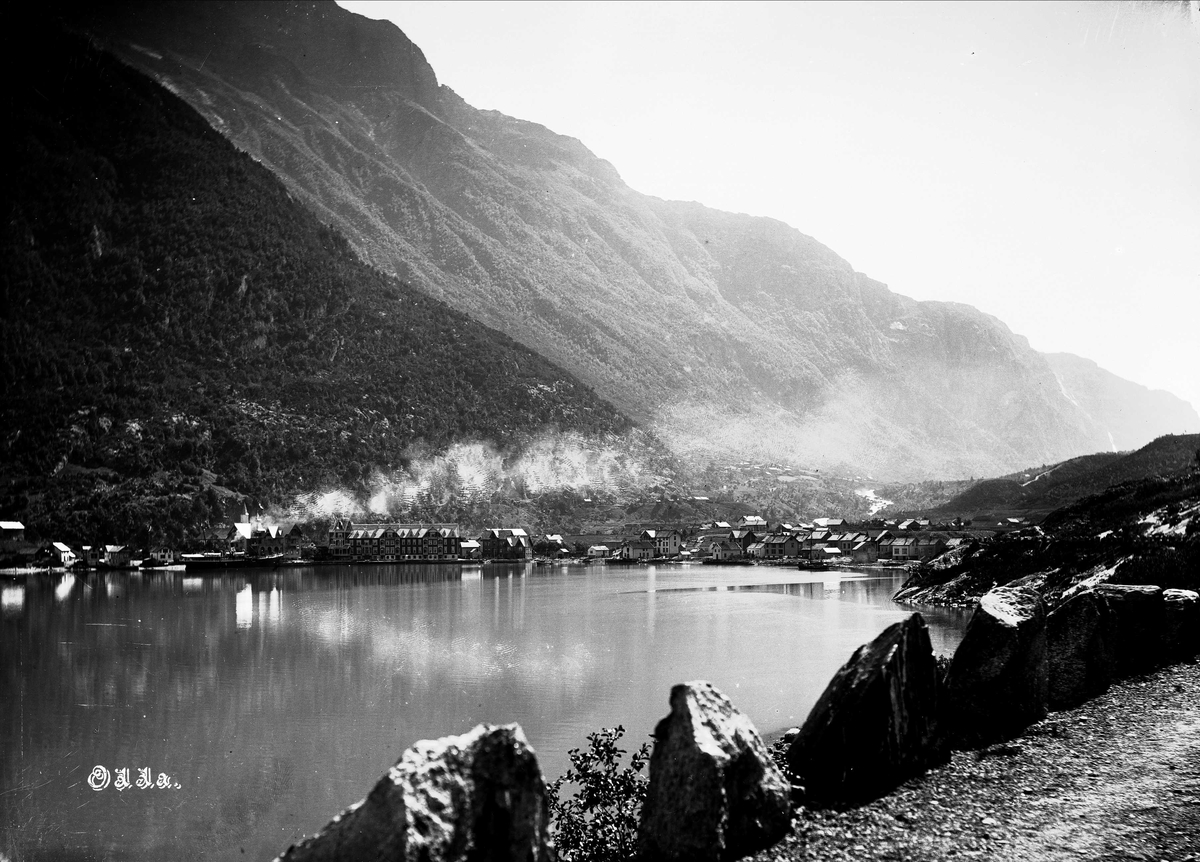 Solveig Lund, Landskapsfotografi fra Odda i Hardanger. I bakgrunnen sees antakelig Opoelva og i forgrunnen Sørfjorden og til høyre en landevei. I midten sees Odda med kirken og Hardanger hotell.