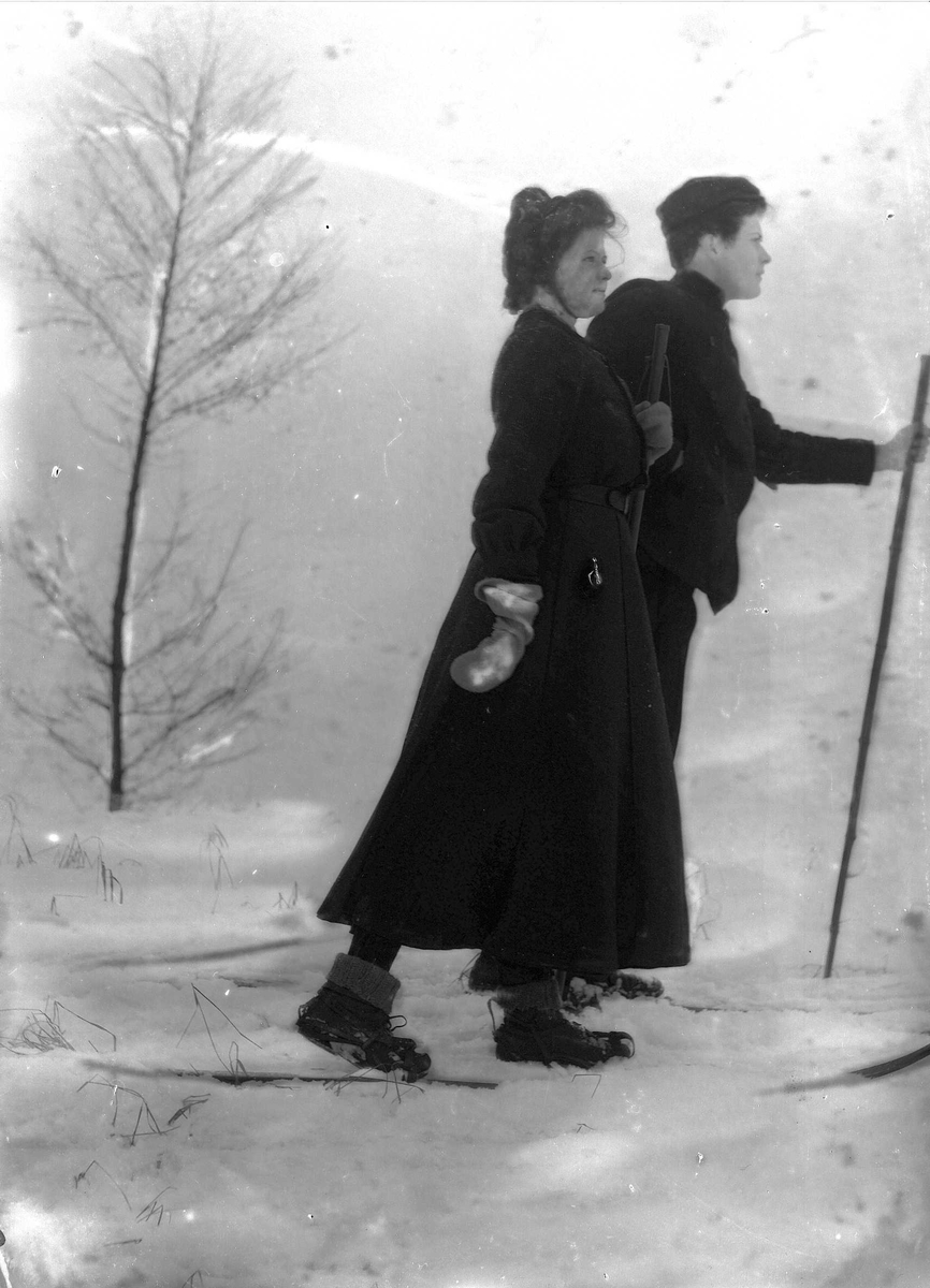 Solveig Lund, Kvinne og mann i snødekt landskap. Fotografert fra siden. Begge har ski på beina.
