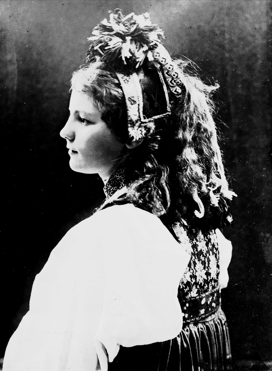 Solveig Lund, Studioportrett av kvinne i drakt og hodeplagg. Avfotografert fra siden.
