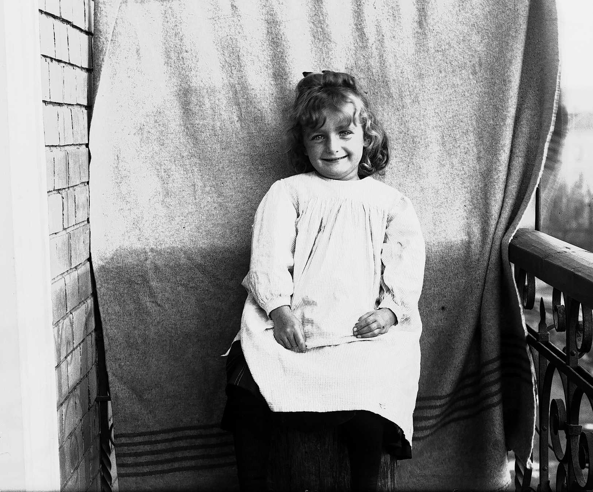 Axel Quinsgaard Wiborg, Karen Q. Wiborg fotografert på balkong, ant. Meltzers gate 9, Oslo, 1899, mot opphengt bakteppe.