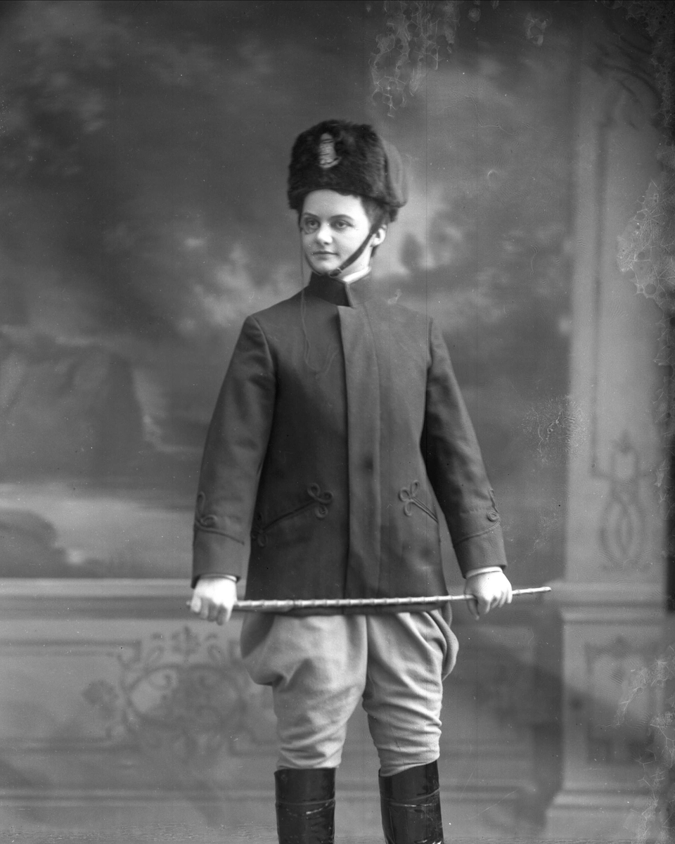 Gustav Borgen, Portrett, kvinne oppkledd i uniform med ridepisk og lorgnett. Skøyen, (Høstmanøvre). Erna Bergh.