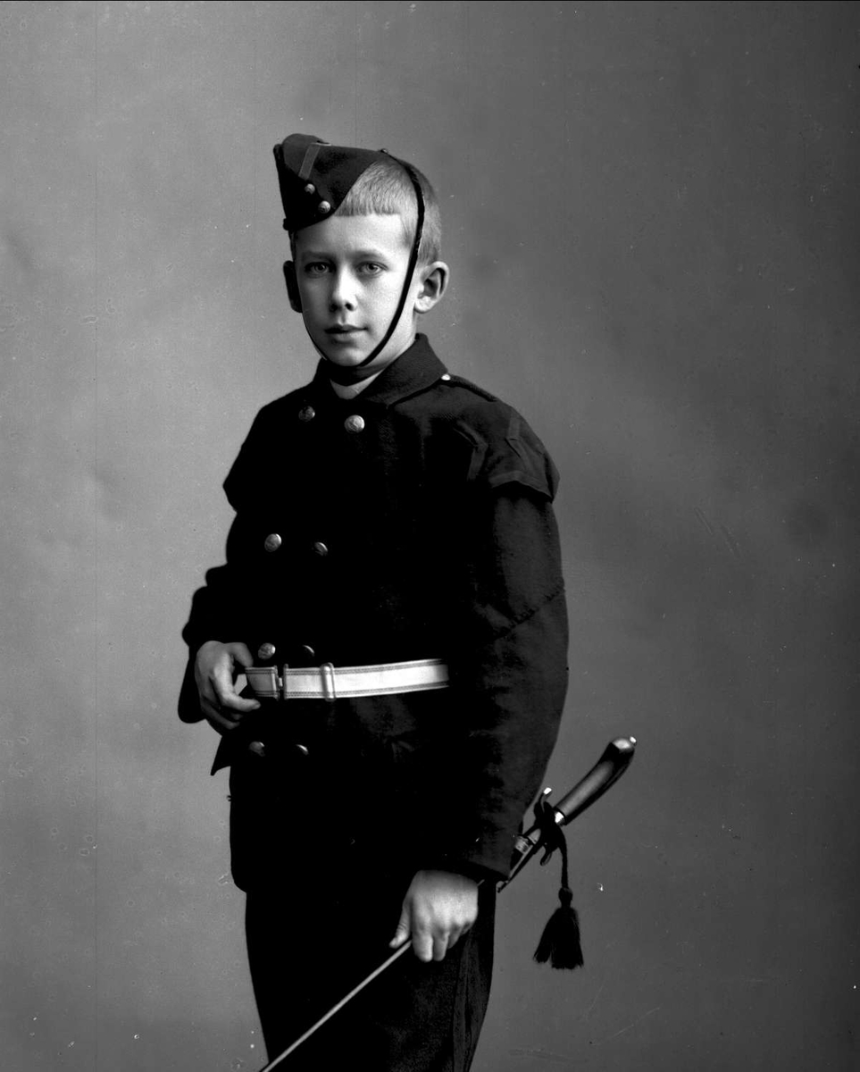 Gustav Borgen, Portrett, gutt i uniform. Buekorpsuniform, sannsynligvis Urania Garde. Uniformslue, med sidevåpen. Gunnar Heide, f. 1885.