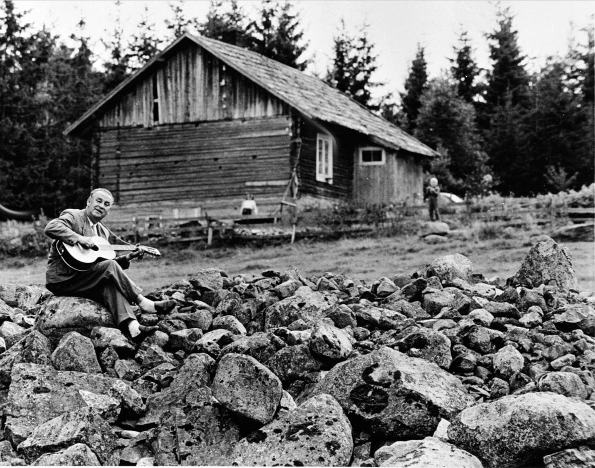 Anno Domkirkeodden, Alf Prøysen med gitar, steinrøysa neri bakken, Prøysenstua, Rudshøgda, Ringsaker.