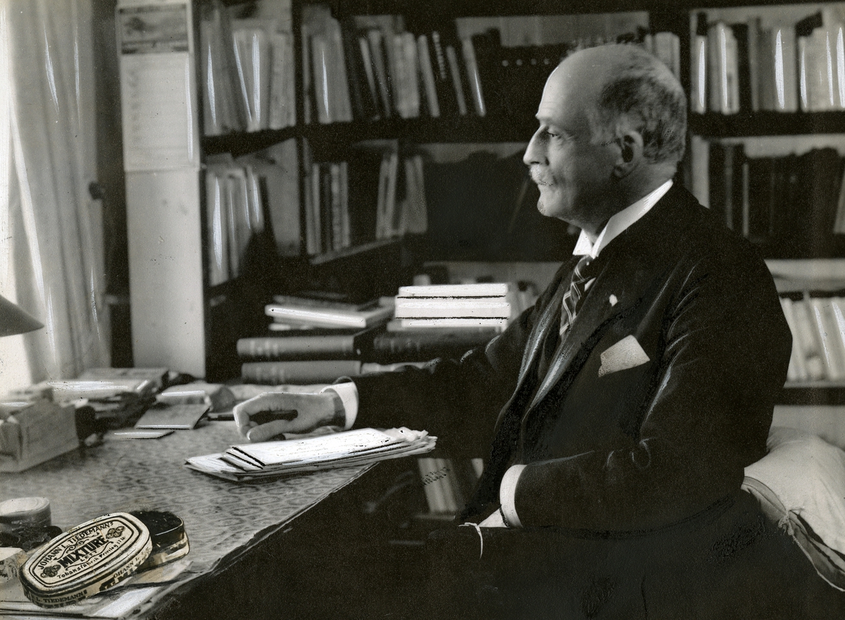 Anders Beer Wilse, Portrett fra serien "Tidens menn om Tiedemann" laget av reklameavdelingen på J. L. Tiedemanns Tobaksfabrik. Til alle portretter hører sitater og signaturer. Her Knut Hamsun. Foto av boks med Tiedemanns Mixture tobakk er limt inn på portrettet.